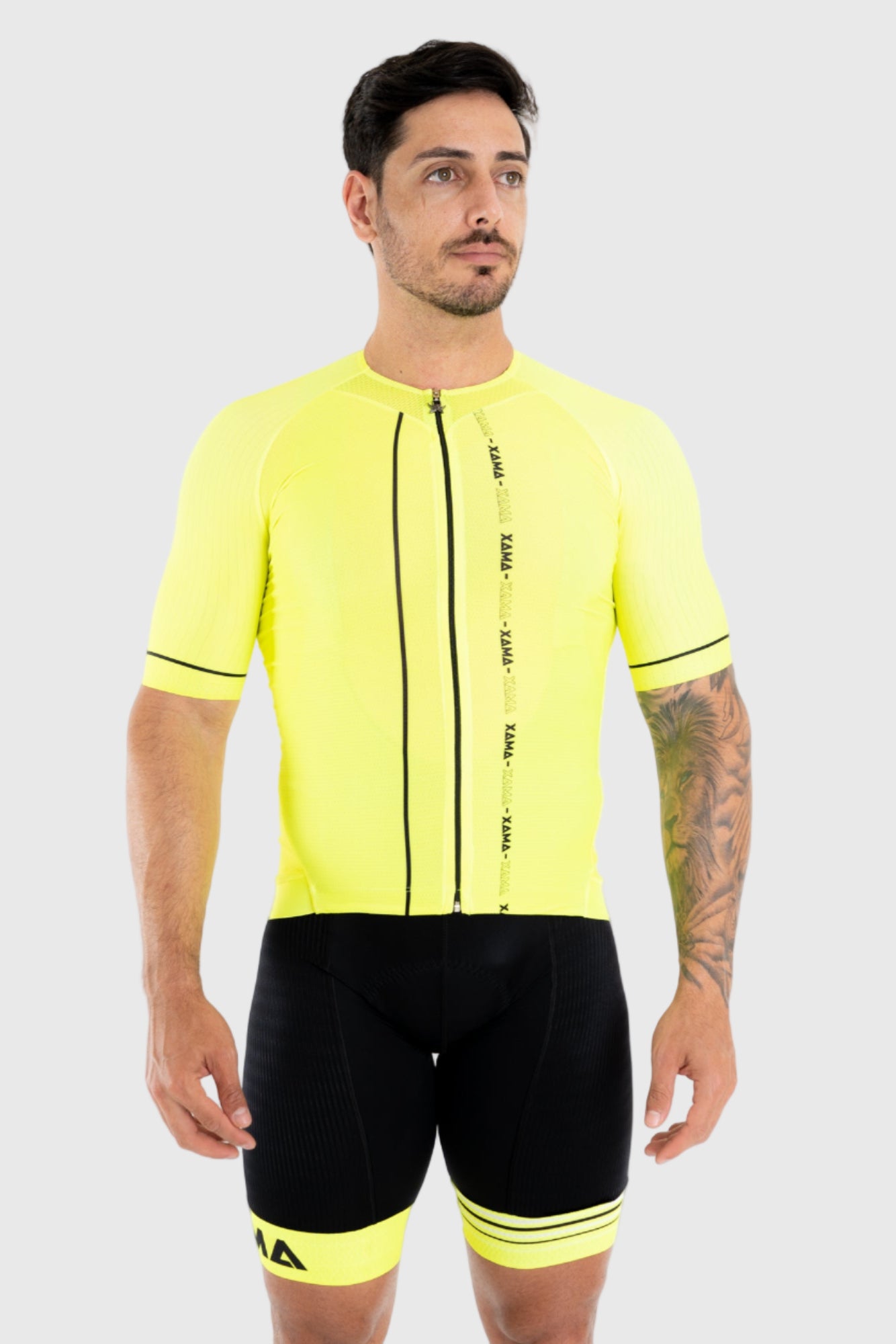 A man wearing a neon yellow cycling top with black short sleeves and a front zipper, paired with black cycling shorts.
