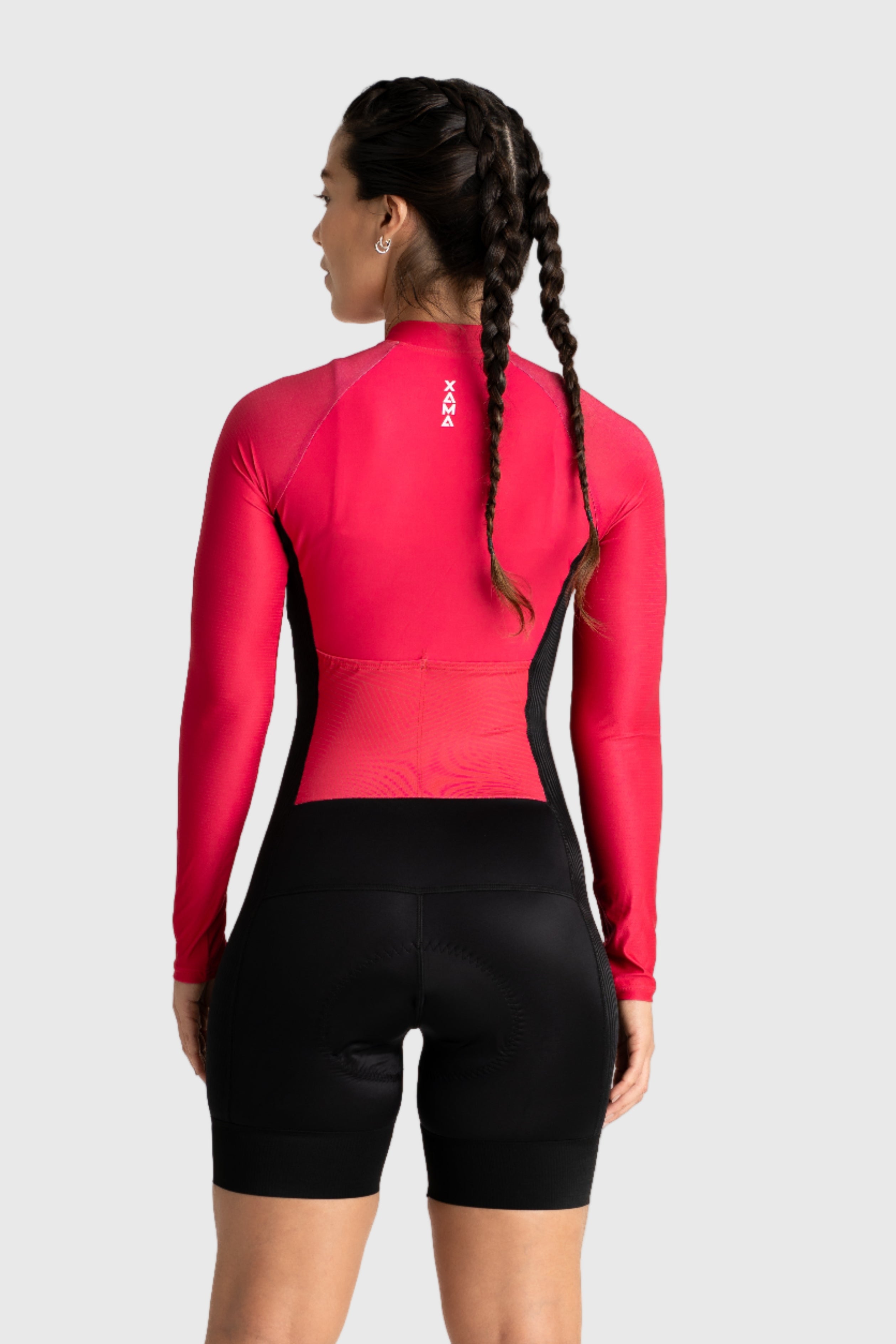 Person wearing a red long-sleeve athletic top and black shorts on a white background