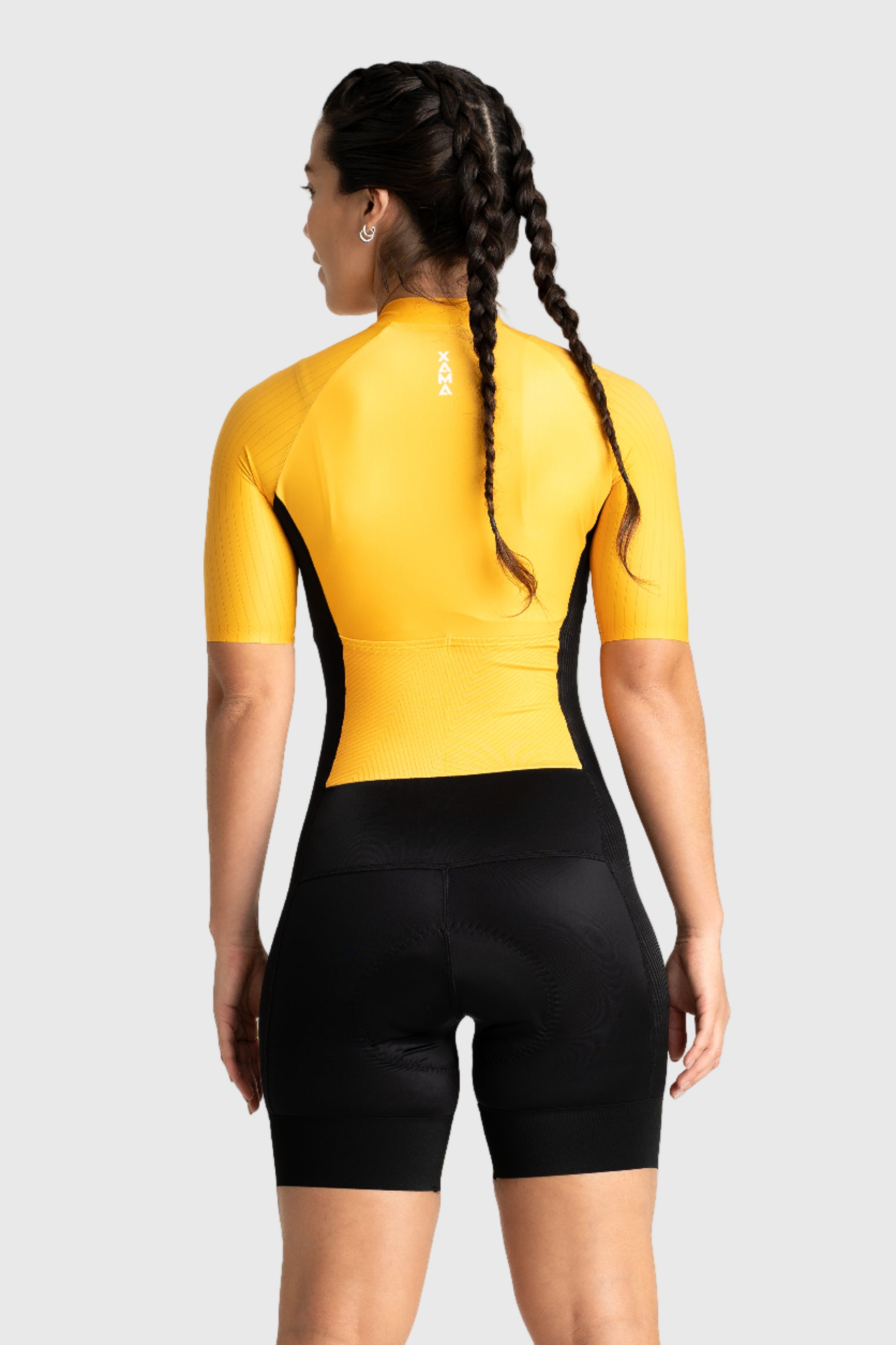 Person wearing a yellow cycling jersey and black shorts on a white background