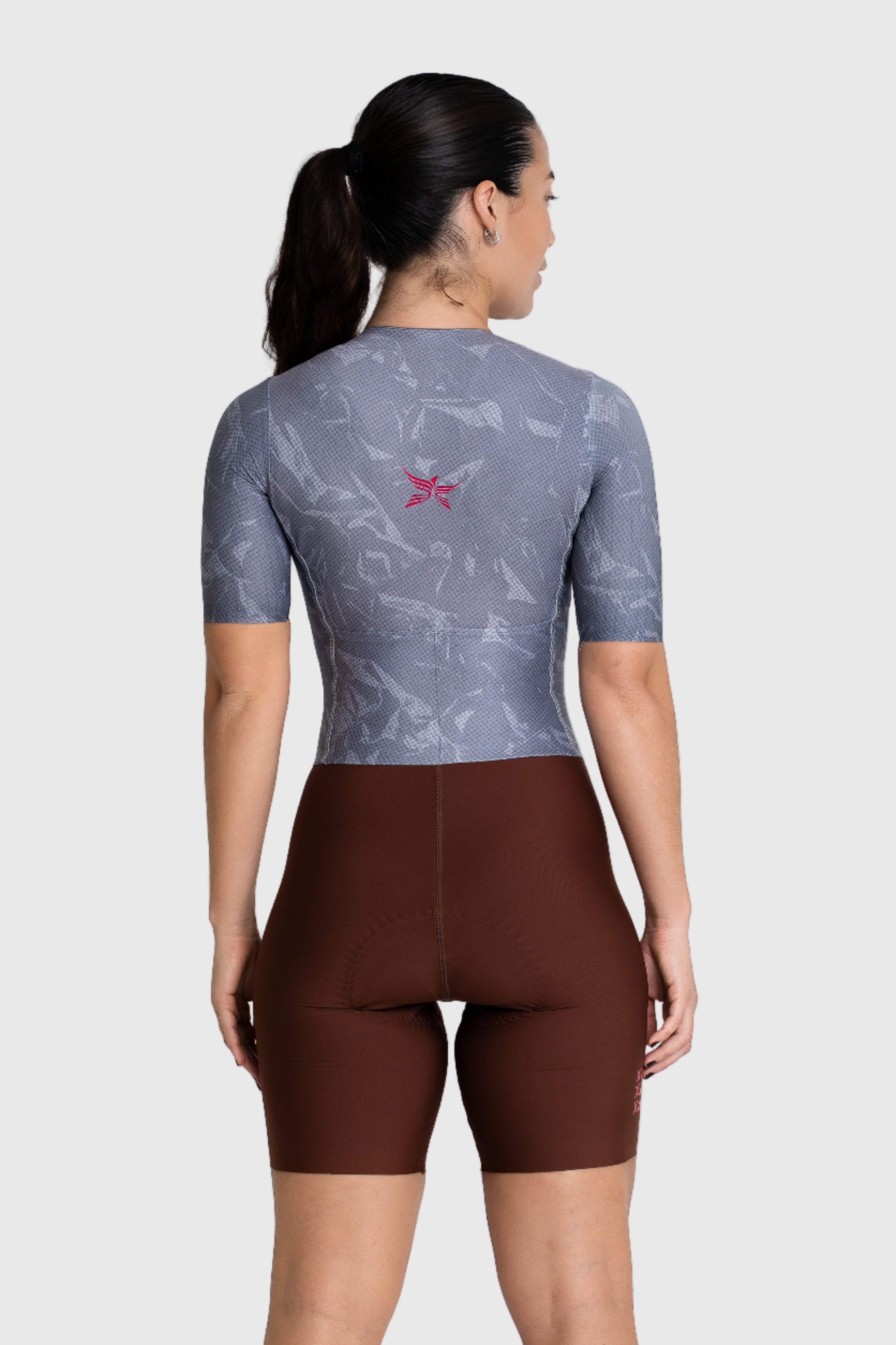 Person wearing a gray cycling jersey and brown shorts on a white background