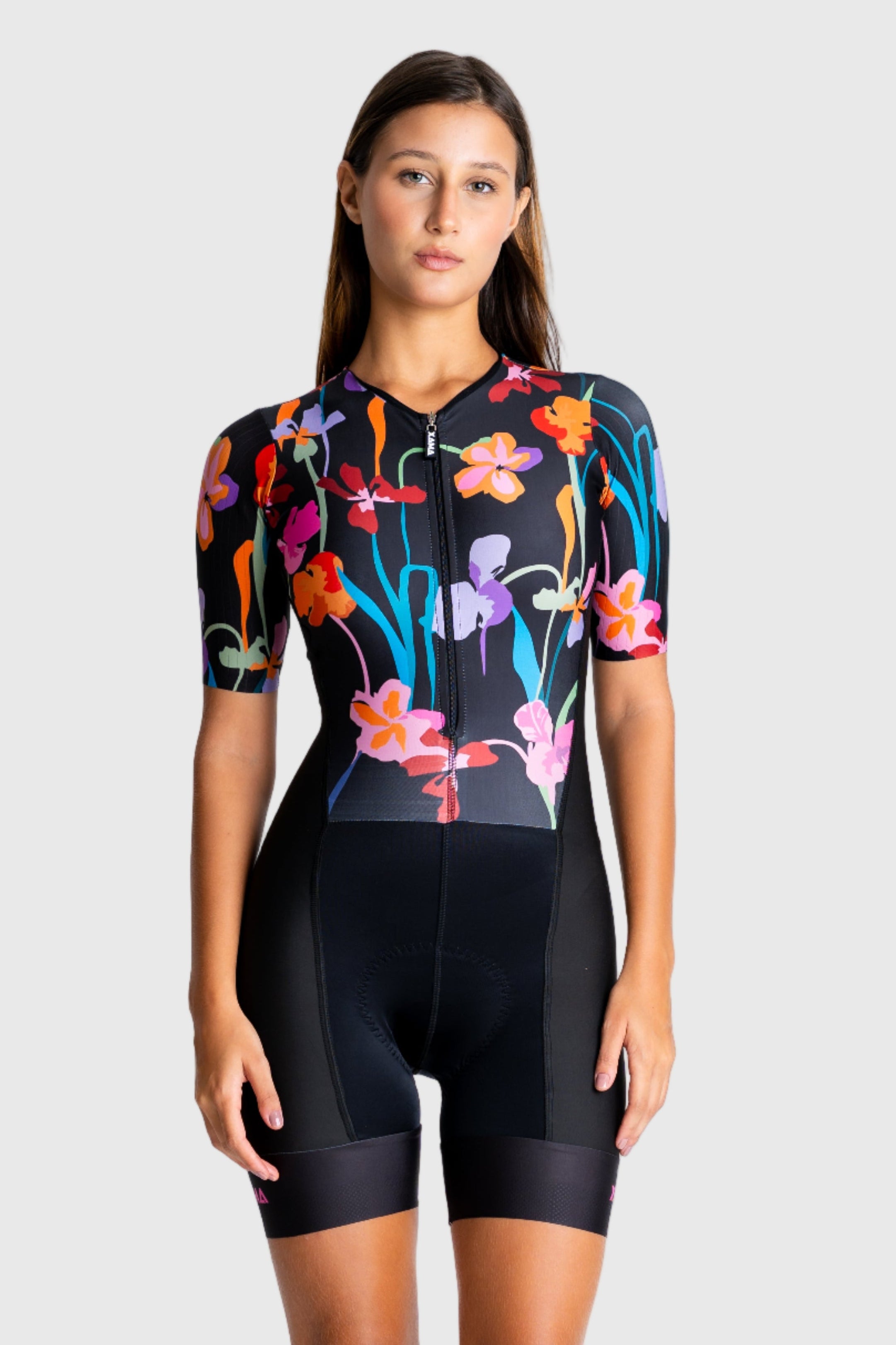 Woman wearing a colorful floral cycling jersey and black shorts on a white background