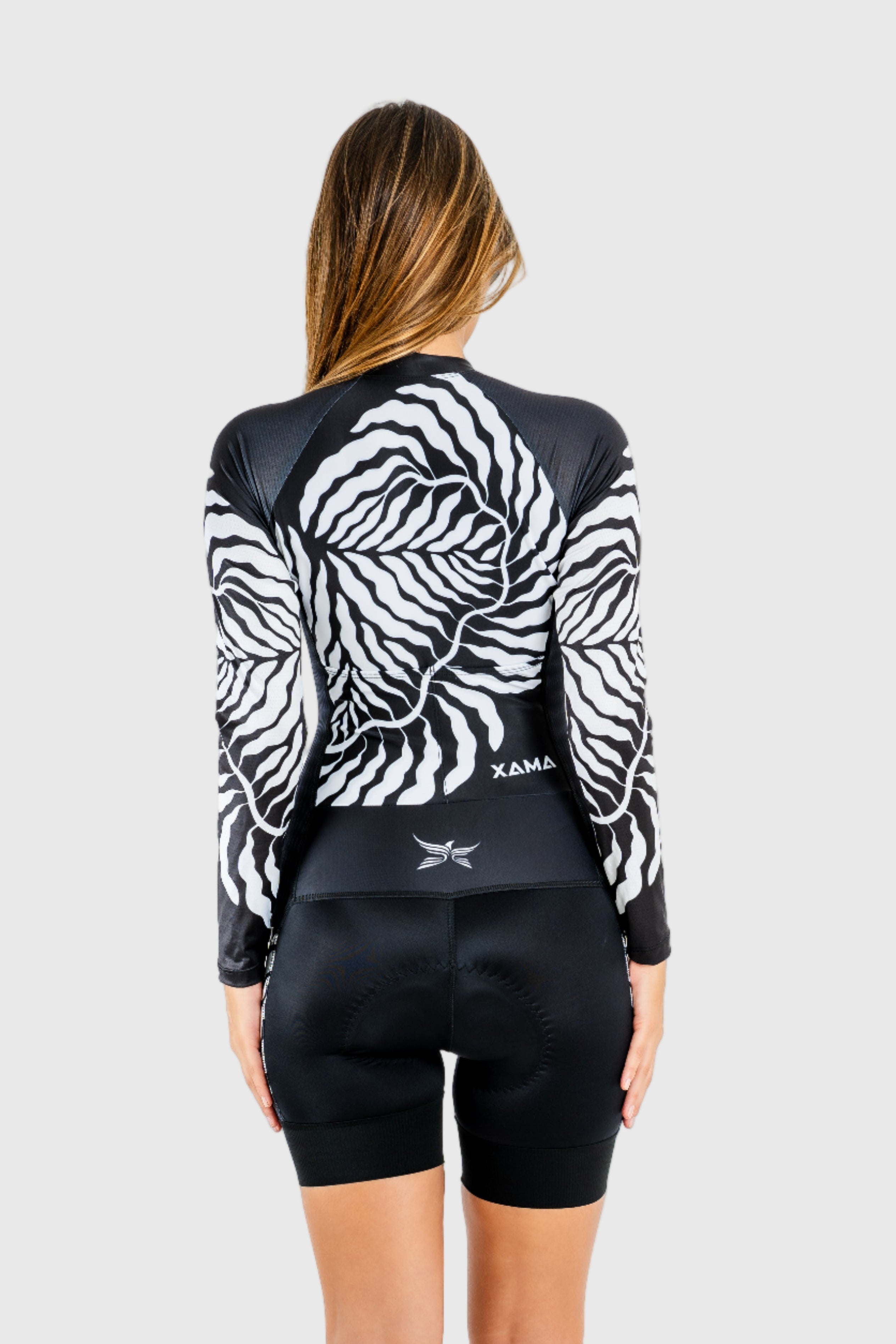 Person wearing a black and white patterned long-sleeve shirt and black shorts on a white background