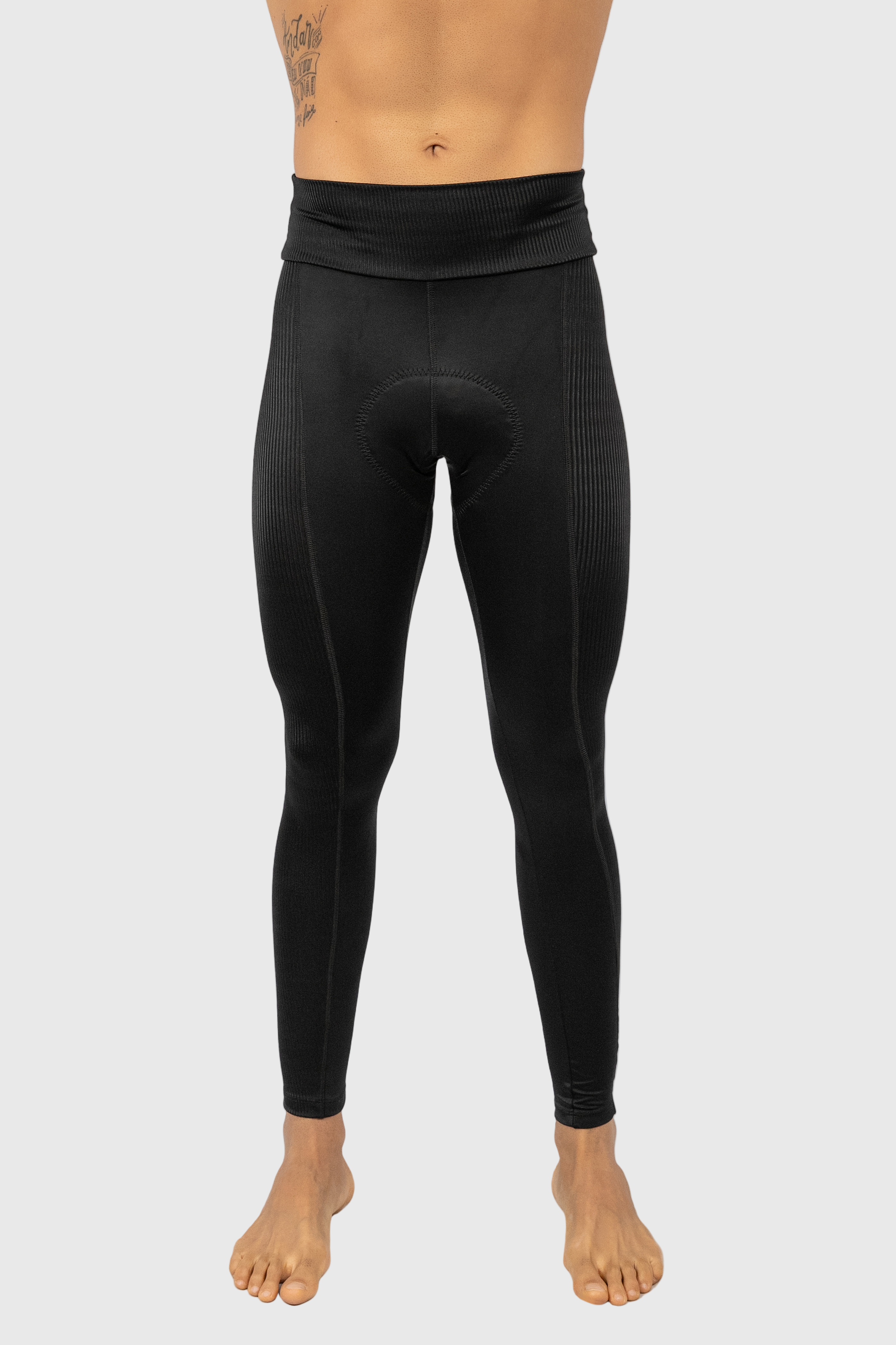 A pair of men's black pants, likely to be tights or leggings, posed on a model with visible feet and ankles.