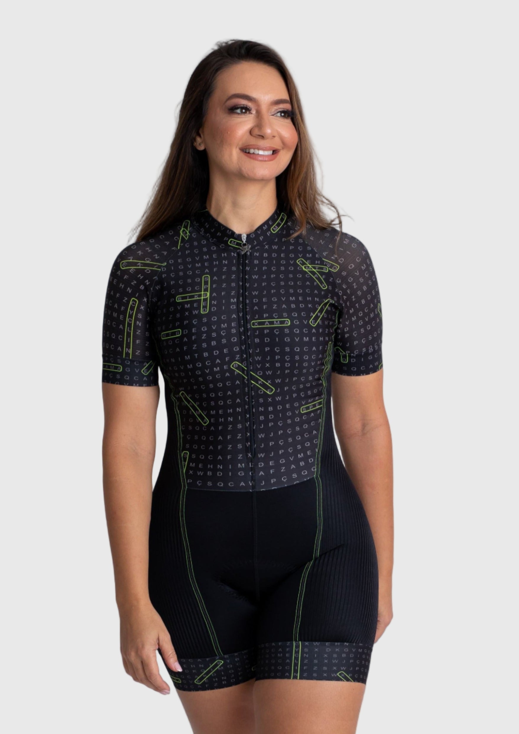 Woman wearing a black cycling outfit with green patterns on a white background
