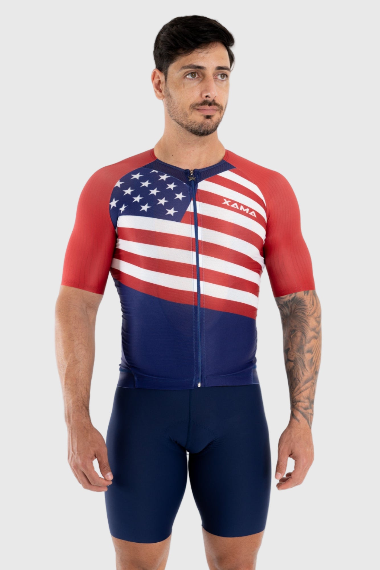 A man wearing a sleeveless cycling top with a patriotic design featuring the American flag in red, white, and blue colors, and the logo 'Xama' on the chest.