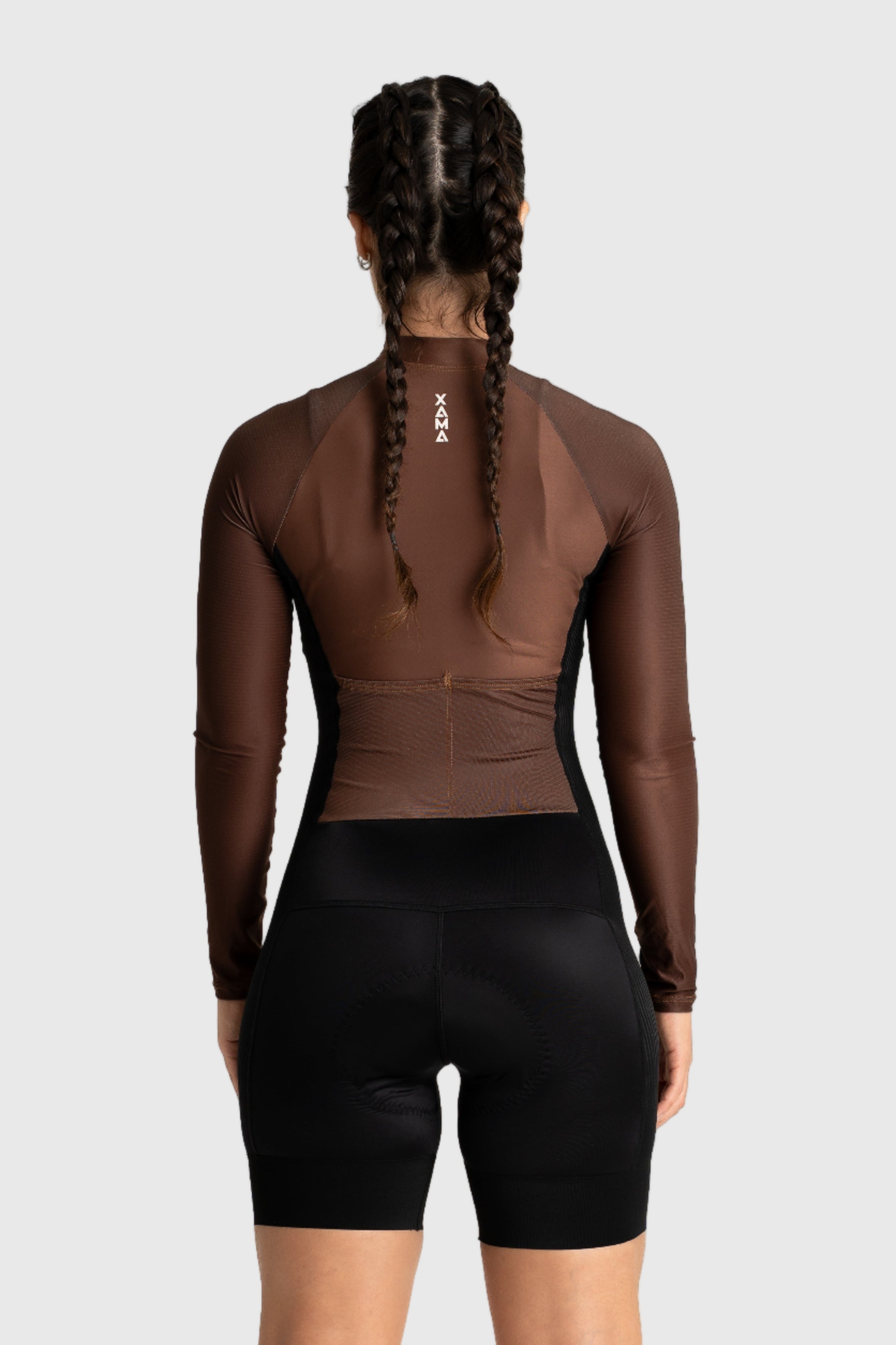 Person wearing a brown long-sleeve top and black shorts on a white background