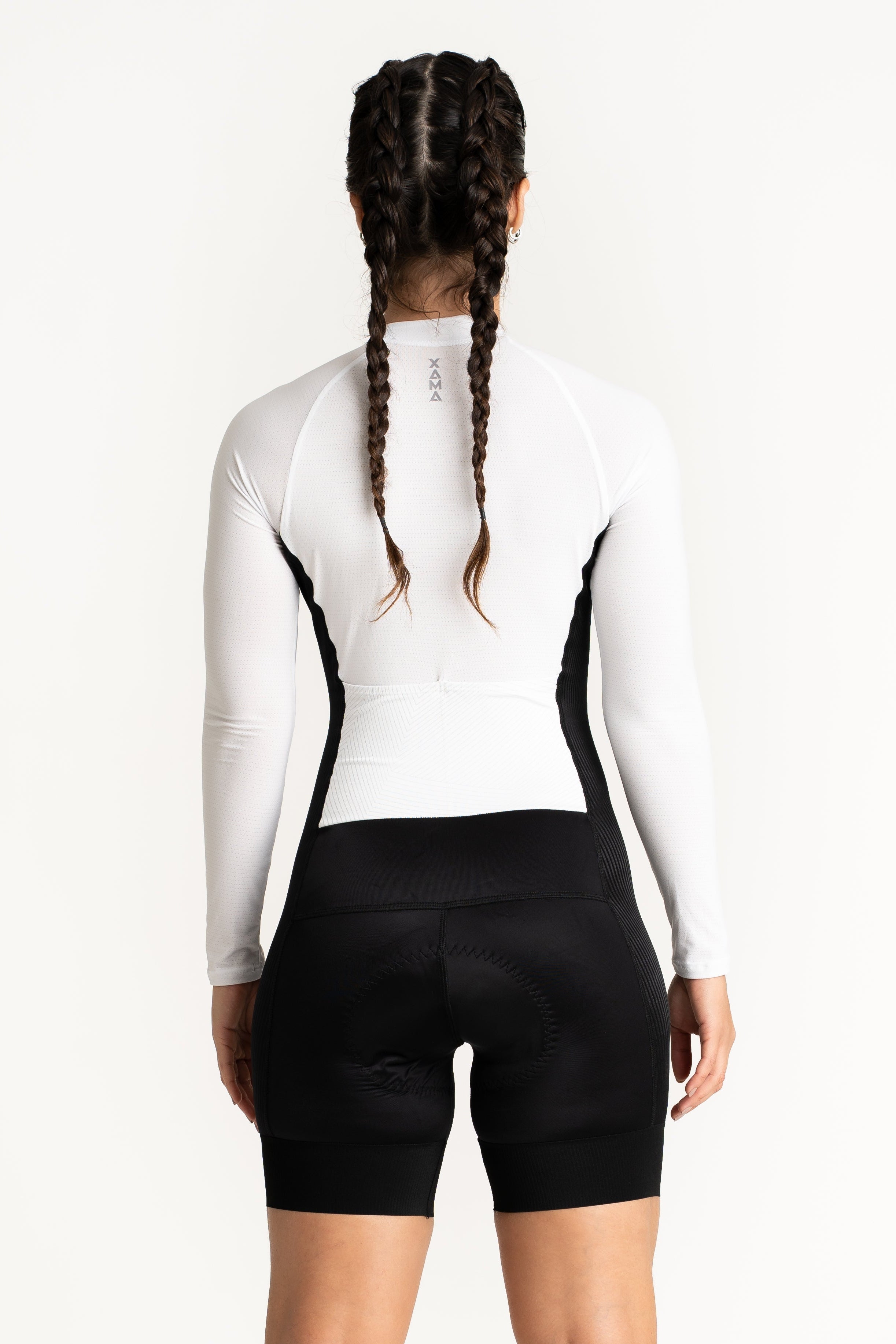 Person wearing a white long-sleeve top and black cycling shorts on a white background