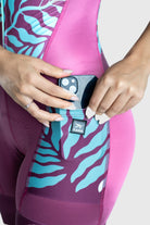 Person wearing pink and purple athletic leggings with a pattern, holding a phone.