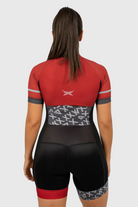 Person wearing a red and black cycling outfit with a geometric pattern on a light gray background