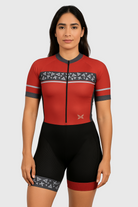 Woman wearing a red and black cycling outfit with geometric patterns on a light gray background