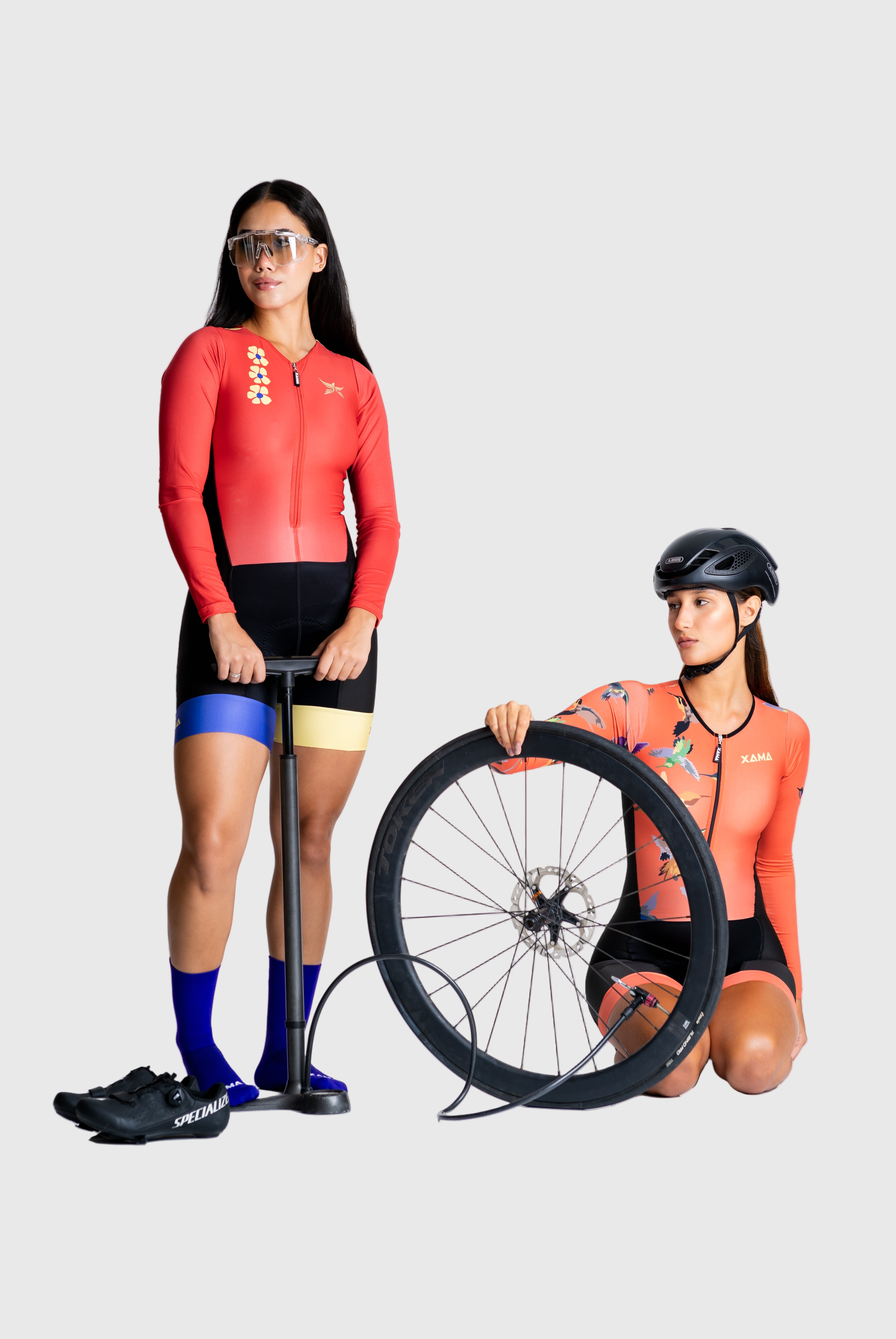Two people wearing cycling outfits with a wheel on a white background