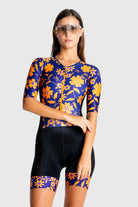 Woman wearing a colorful cycling outfit with a blue and orange floral pattern on a white background