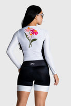 Person wearing a white cycling outfit with a colorful flower design on the back, standing against a white background.