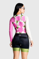 Woman wearing a pink floral cycling jersey with black shorts on a white background