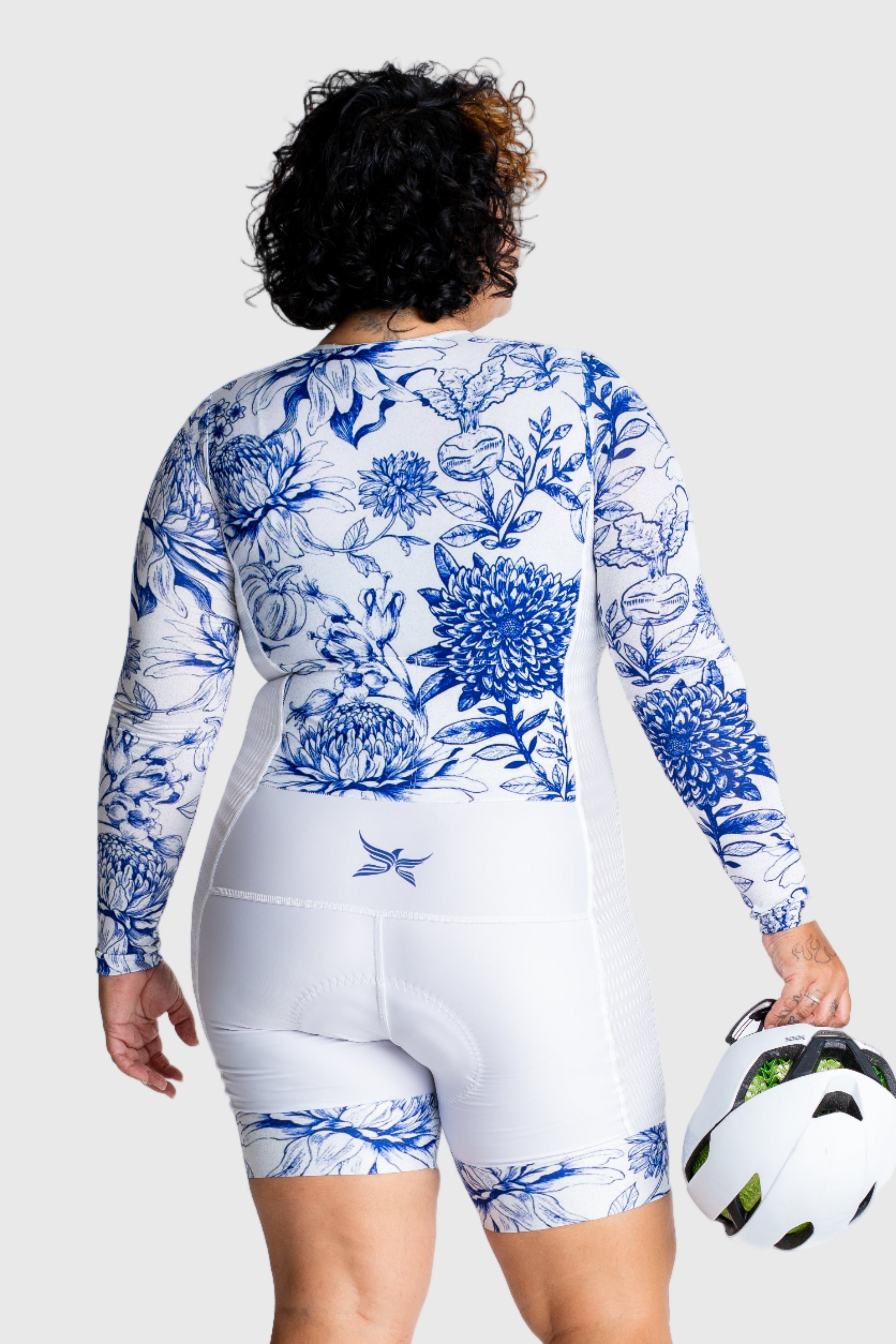 Person wearing a blue and white patterned athletic outfit holding a bike helmet on a white background