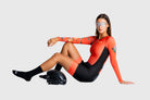 Woman in a red and black wetsuit with a helmet on a white background