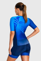 Woman wearing a blue athletic outfit with a design on the back against a white background