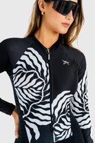 Person wearing a black and white patterned jacket with a brand logo on a white background