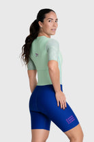 Woman wearing a light green top and blue cycling shorts on a white background