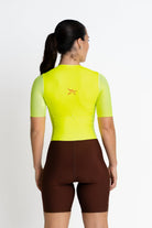 Person wearing a bright yellow cycling jersey and brown shorts on a white background