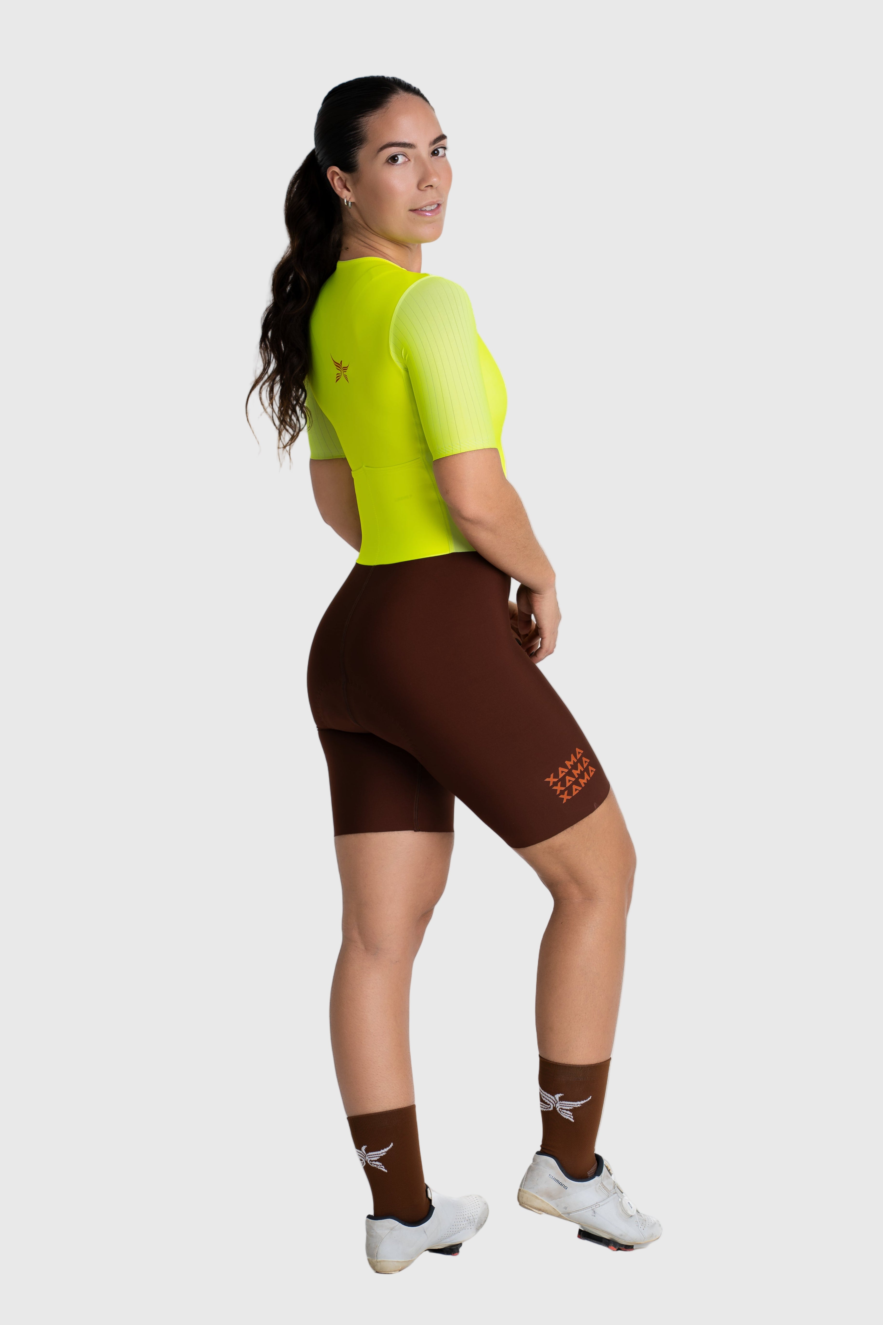 Person wearing a bright yellow cycling jersey and brown shorts on a white background