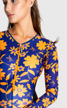 Woman wearing a blue and yellow floral long-sleeve top on a white background