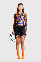 Woman wearing a colorful cycling outfit with a helmet on a white background