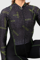Person wearing a black cycling outfit with neon green accents on a white background