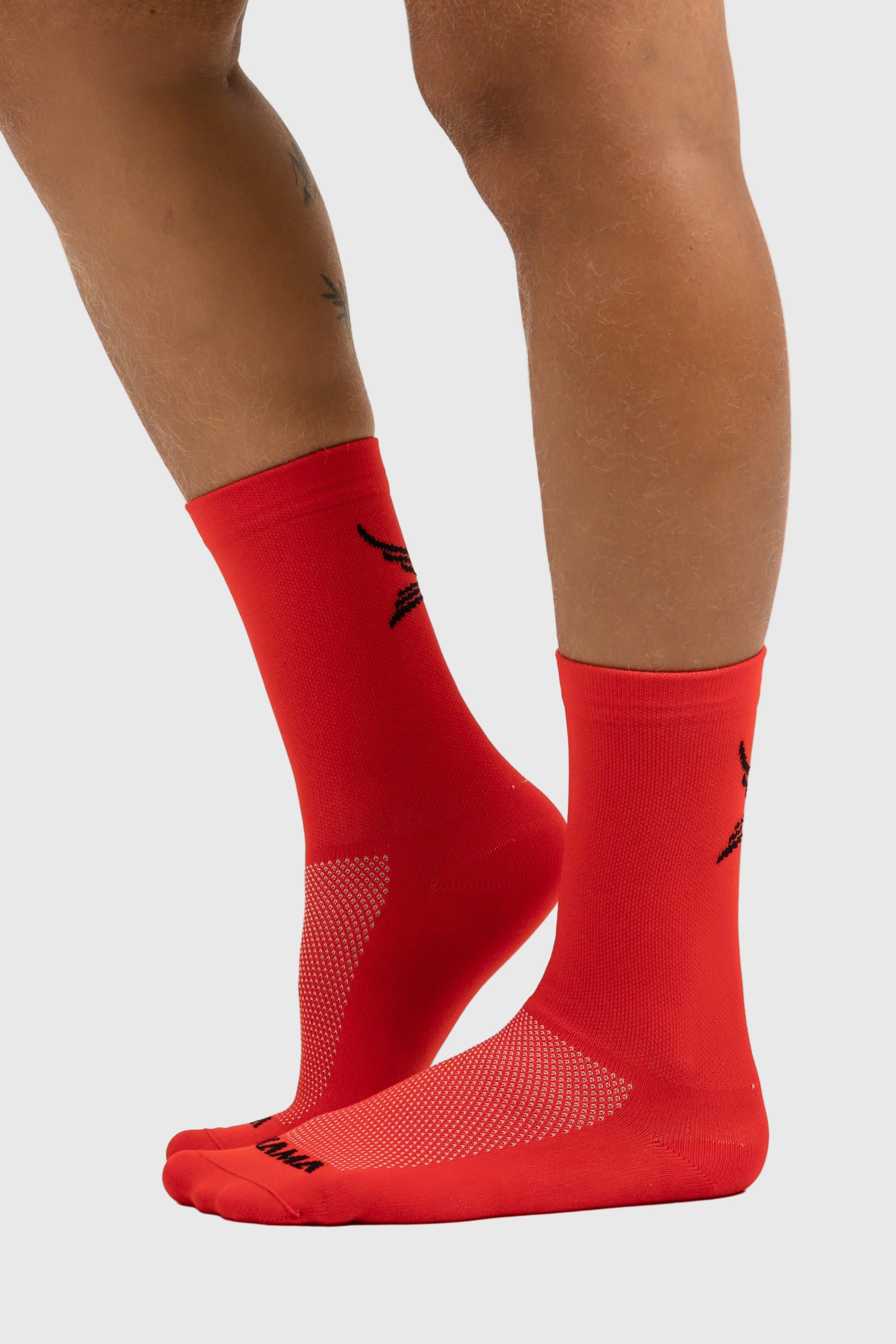 A pair of red sports socks with a logo visible on the upper part, worn on a person's legs against a white background.