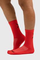 A pair of red sports socks with a logo visible on the upper part, worn on a person's legs against a white background.
